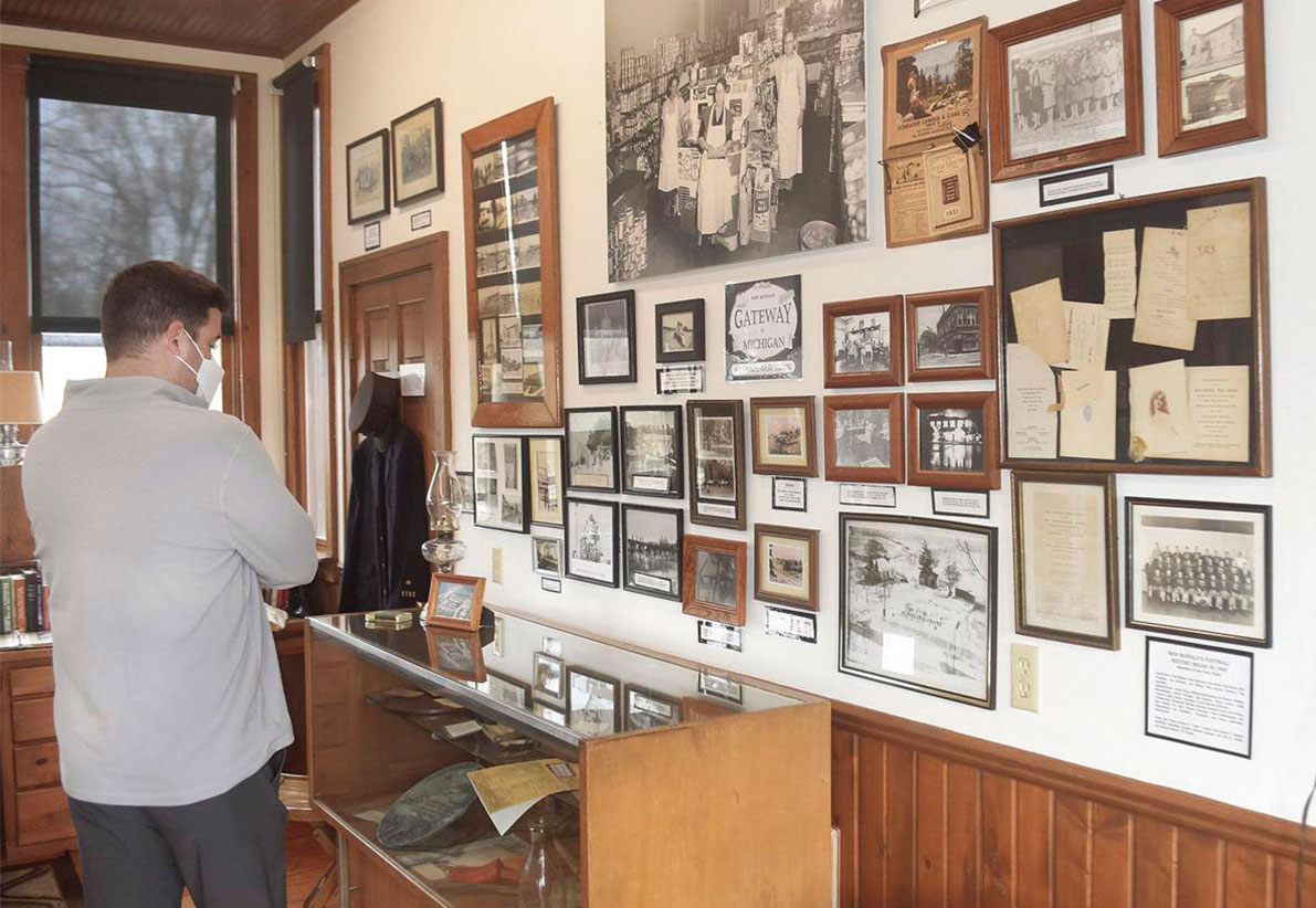 Man standing in museum room looking at old photos and memorabilia 