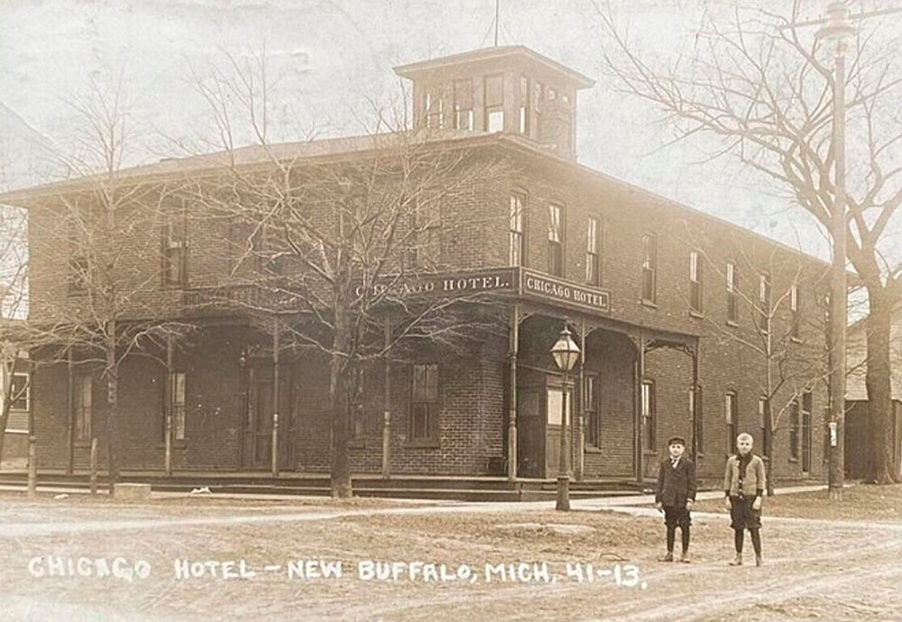 antique photo of two young boys standing in front of a large brick building labeled Chicago Hotel